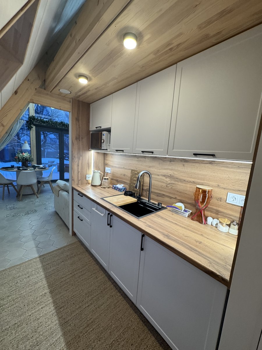 Современная кухня A-frame дома со светло-серыми шкафами, деревянной столешницей и фартуком