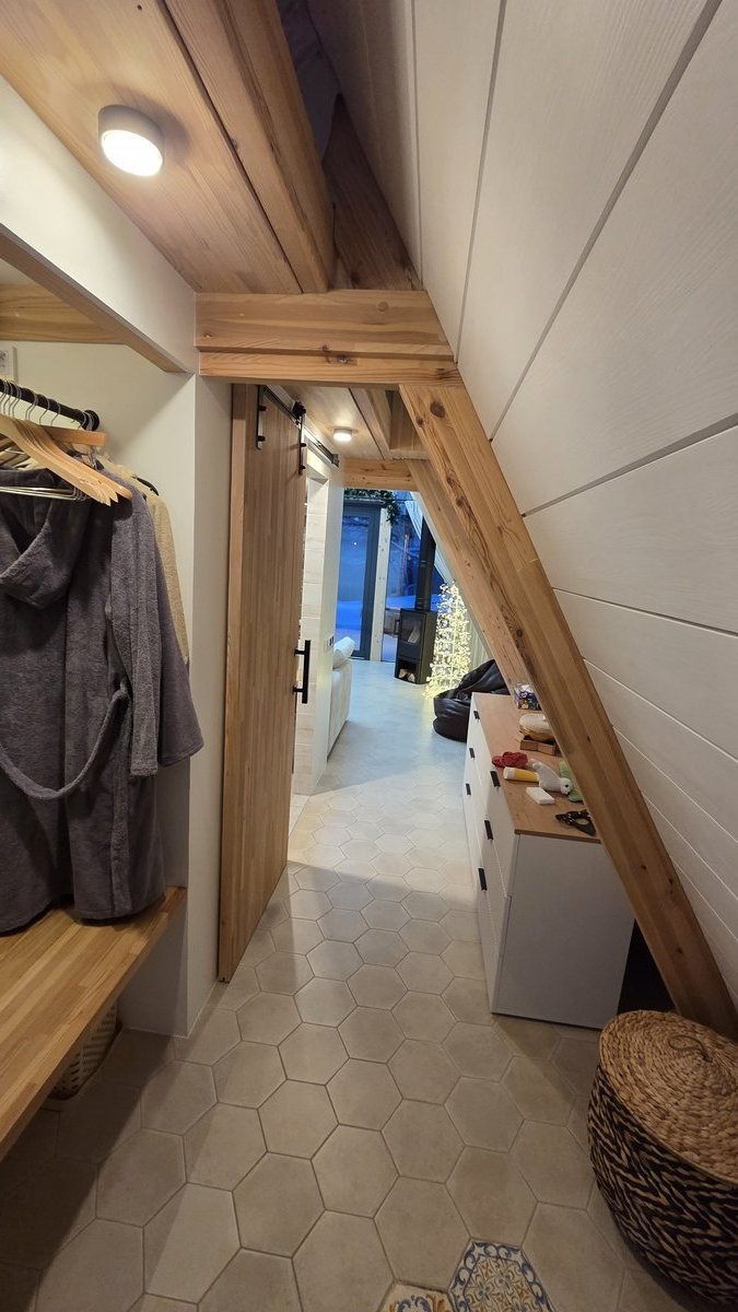 Прихожая A-frame с раздвижной деревянной дверью, вешалкой для халатов и гексагональной плиткой